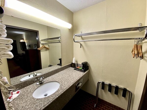 Une salle de bain d’hôtel équipée d’un lavabo, d’un miroir, d’un porte-serviettes et d’un sèche-mains.