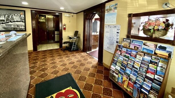 A reception area with a tiled floor, a reception desk, a computer, and a display of travel brochures. - Super 8 By Wyndham Shawnee (Shawnee)