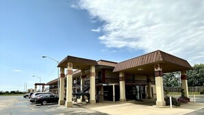 A gas station with multiple fuel pumps, a covered waiting area, and a parking lot with several cars. - Super 8 By Wyndham Shawnee (Shawnee)