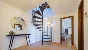 A modern interior with a spiral staircase, a round mirror, a console table, and a woven rug. - Cubo's Casa Rural Pulpito / air conditioning / free wifi / private pool (Coín)