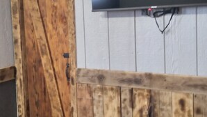 Une pièce dotée d’une porte en bois, d’un téléviseur à écran plat fixé au mur et d’une petite table sur laquelle sont posés des appareils électroniques.