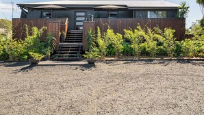 Una casa moderna de dos pisos con entrada de grava, valla de madera y plantas en macetas.