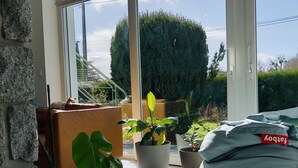 A bright room with large windows, a stone wall, and several potted plants. - Jolie Maison Familiale sur la ria à Saint-cado (Belz)