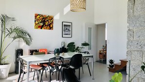 A modern dining area with a white table, black chairs, and a large potted plant. - Jolie Maison Familiale sur la ria à Saint-cado (Belz)