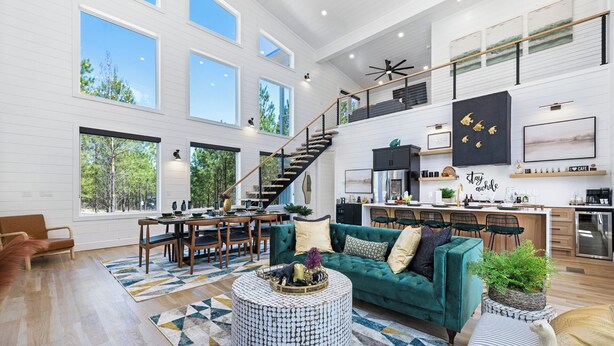 A spacious living area with a large sofa, a dining table, and a kitchen in the background. - Luxury 3BR in ❤️ of Hochatown! Heated Pool, Playset, Games (Broken Bow)