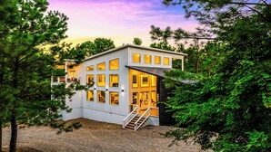 A modern two-story house with large windows, surrounded by trees. - Luxury 3BR in ❤️ of Hochatown! Heated Pool, Playset, Games (Broken Bow)