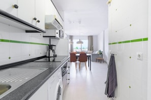 A compact kitchen with a dining area, a washing machine, and a view of the outdoors. - Zeus | Cosy Apartment with Stunning Sea Views & Pool in Riviera del Sol (Mijas Costa)