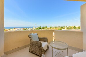 A balcony with a wicker chair and a small table, overlooking a coastal landscape. - Zeus | Cosy Apartment with Stunning Sea Views & Pool in Riviera del Sol (Mijas Costa)
