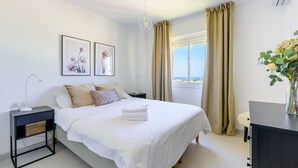 A neatly arranged bedroom with a bed, bedside table, and a view of the outdoors.