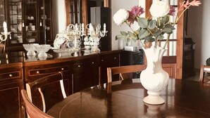 A dining room with a round wooden table, chairs, a white vase with flowers, and a large mirror above the table.