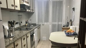 A compact kitchen with a dining area, equipped with basic appliances and a small table with chairs.