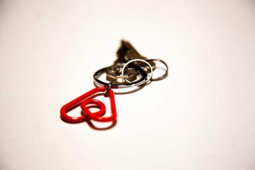A metal keychain with a red plastic loop.