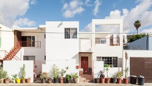 A modern white building with a red staircase, multiple windows, and potted plants. - Sunset Included in your stay !!! (Tijuana)