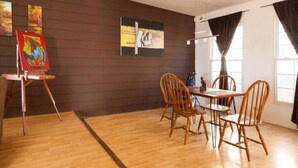 A dining area with a wooden table and chairs, a painting on the wall, and a window with curtains. - Sunset Included in your stay !!! (Tijuana)