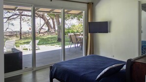 A bedroom with a bed, a TV, and a view of an outdoor patio with chairs and a table. - Playa Prieta Beachfront Villas (Tempate)