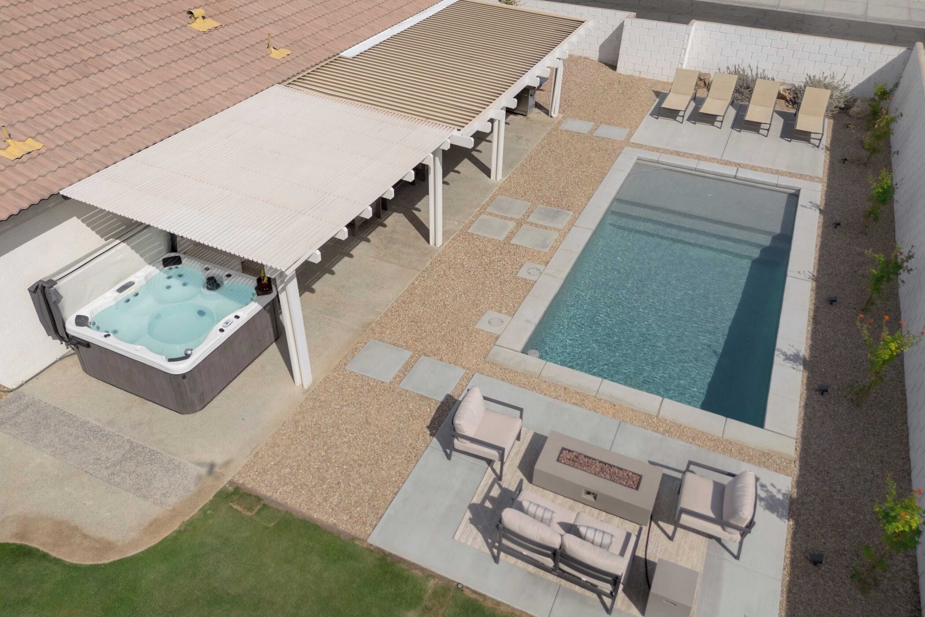 A rooftop pool area with a hot tub, lounge chairs, and a fire pit.