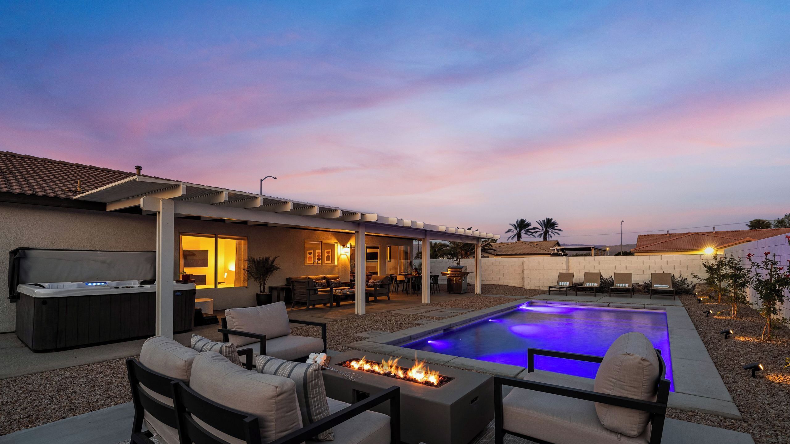 A backyard with a pool, outdoor seating, and a patio area.