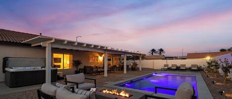 A backyard with a pool, outdoor seating, and a patio area.