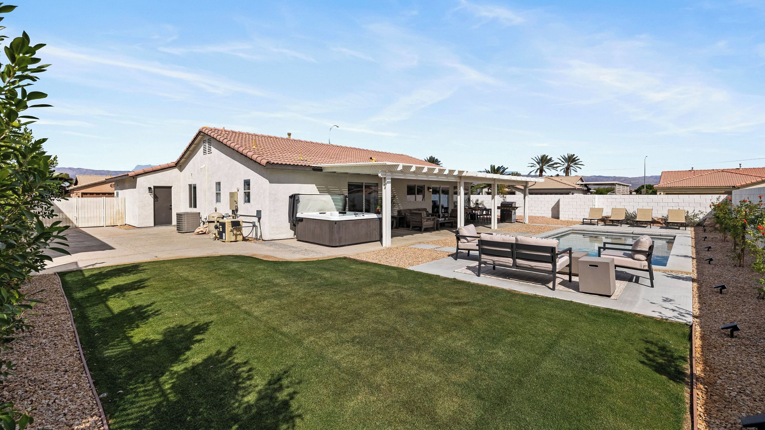 Une maison avec un patio, un jacuzzi et une piscine.