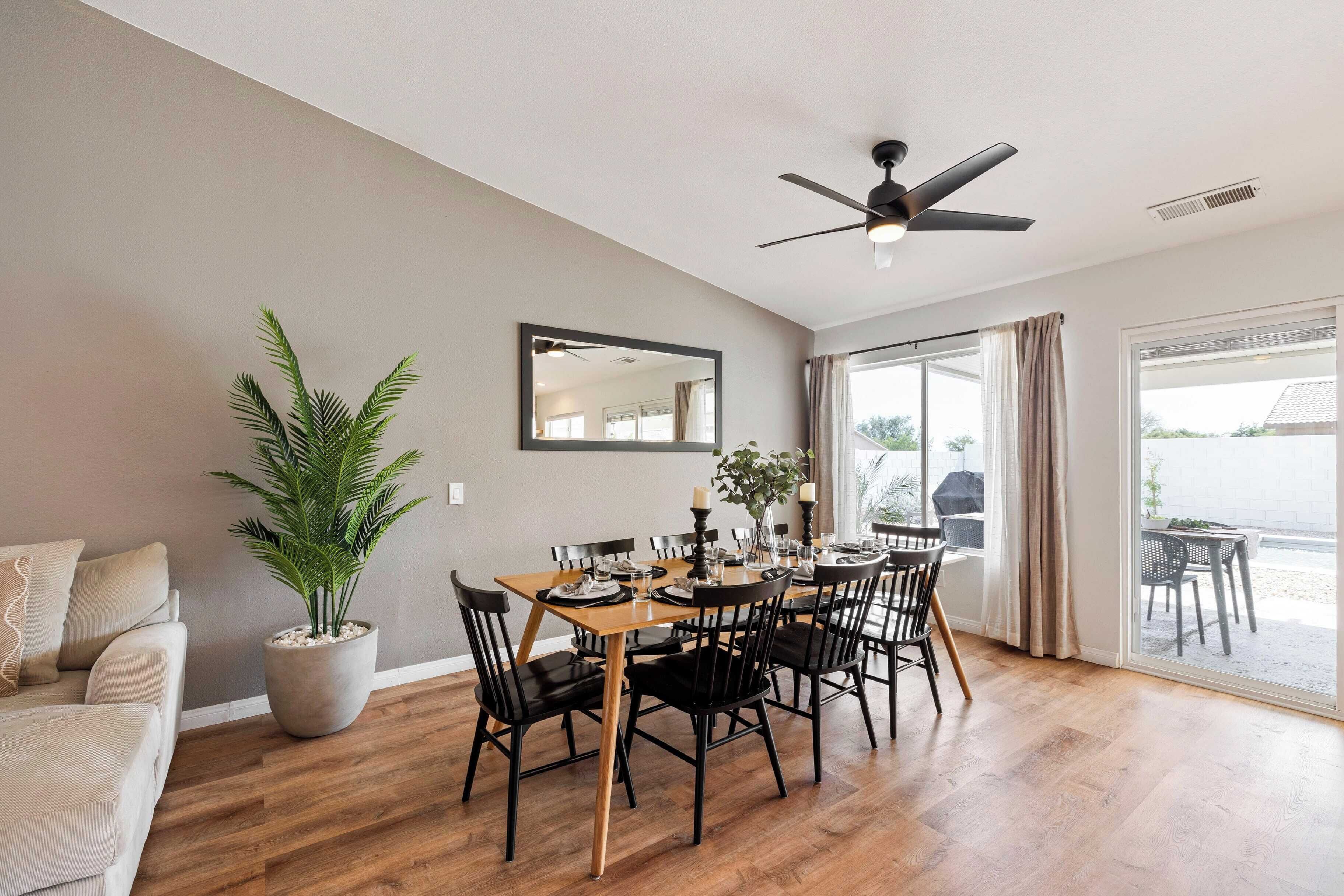 A dining area with a wooden table, black chairs, and a ceiling fan.