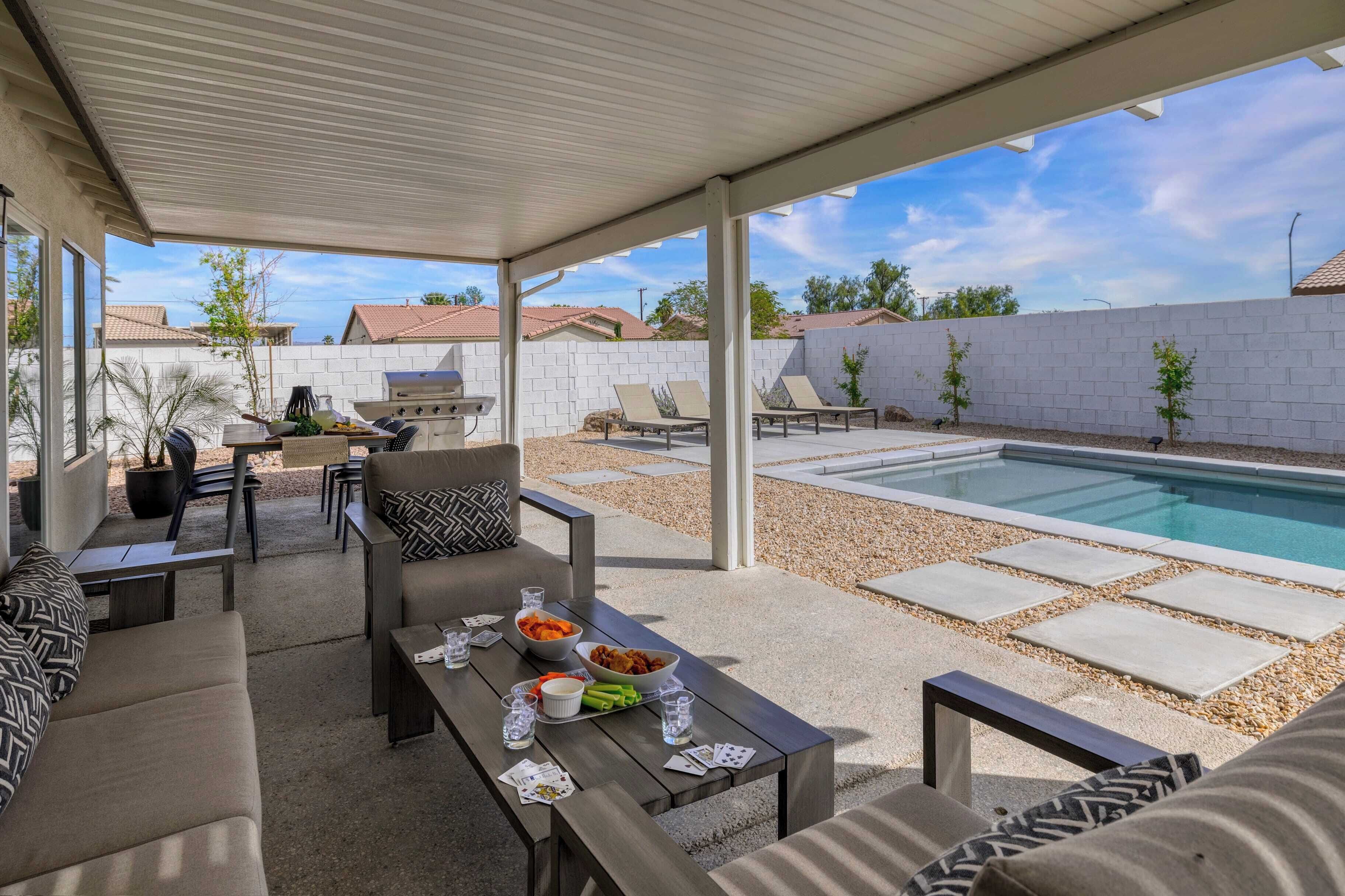 Un espacio al aire libre con piscina, mobiliario y una parrilla.