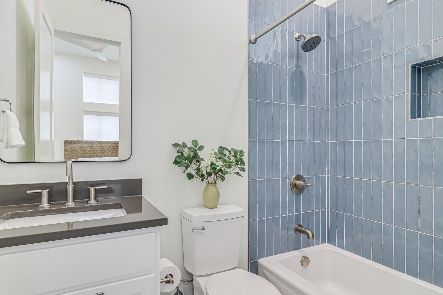 Une salle de bain avec un meuble-lavabo blanc, un miroir, des toilettes et une baignoire.