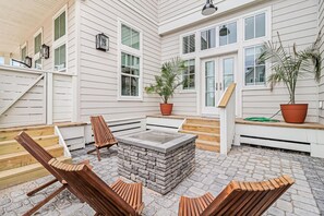 A covered outdoor seating area with wooden chairs and a stone fire pit. - Shore-ty! It's Your Beach Day 127 SEV (Port Aransas)