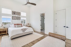 A spacious bedroom with a large bed, a walk-in closet, and a view of the outdoors. - Shore-ty! It's Your Beach Day 127 SEV (Port Aransas)