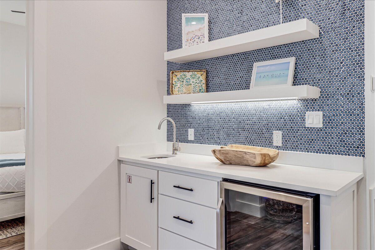 Une salle de bain moderne avec un lavabo blanc, un bol en bois et un mur recouvert de carreaux.