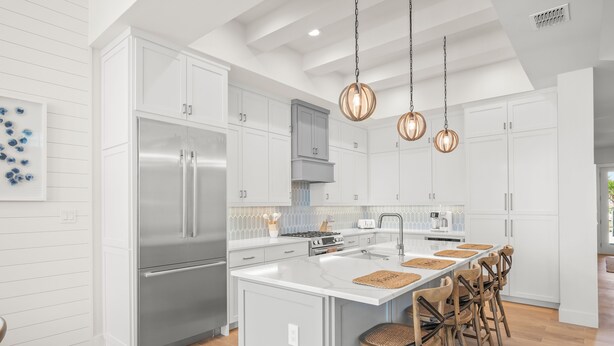 A modern kitchen with white cabinetry, stainless steel appliances, and a central island with bar stools. - Beach Blue 227 LAU (Port Aransas)