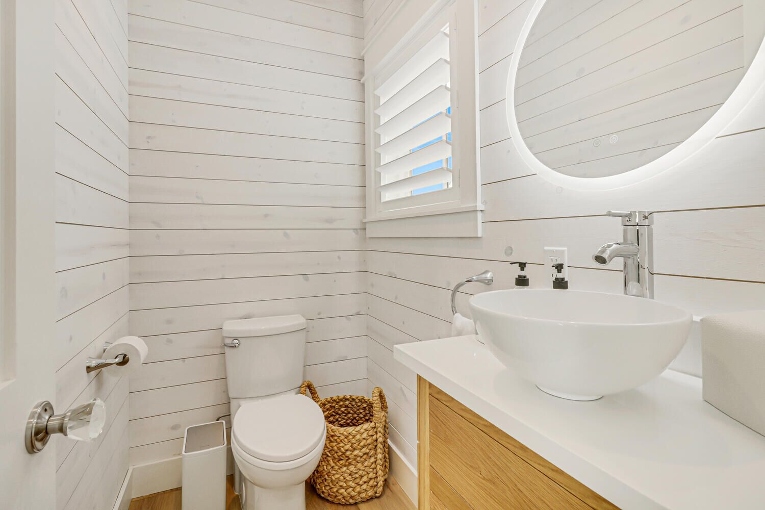 A bathroom with a white toilet, a white sink, and a wooden vanity.