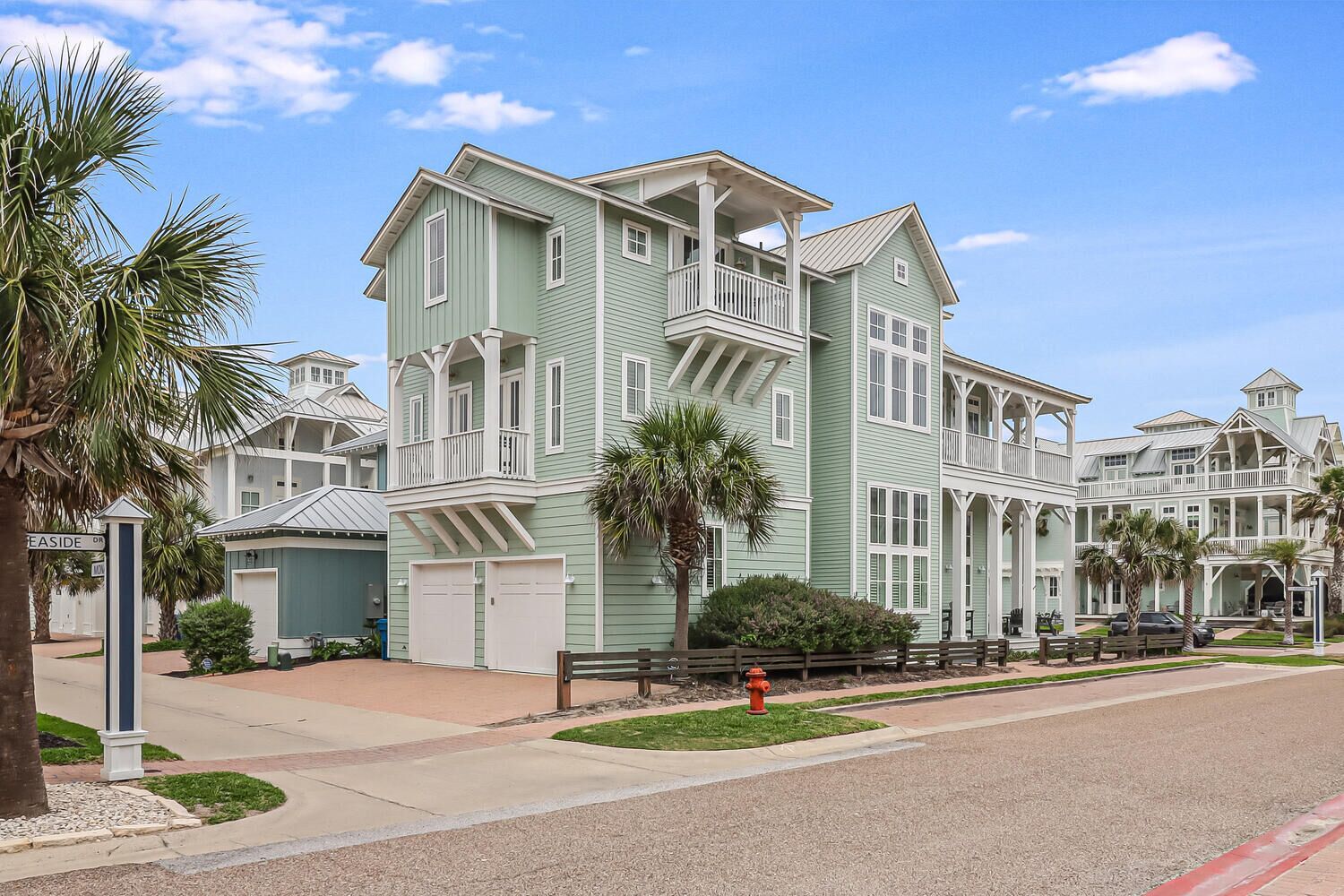 A large, multi-story building with a balcony on the second floor, a garage, and a well-maintained lawn.