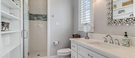 Een moderne badkamer met een inloopdouche, toilet, wastafelmeubel met spiegel en wastafel.