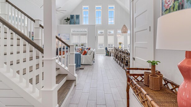 A spacious hallway with a high ceiling, white walls, and a wooden staircase. - Emergensea 200 LAU (Port Aransas)