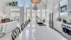A spacious kitchen with a long island, stainless steel appliances, and a large window providing natural light. - Emergensea 200 LAU (Port Aransas)