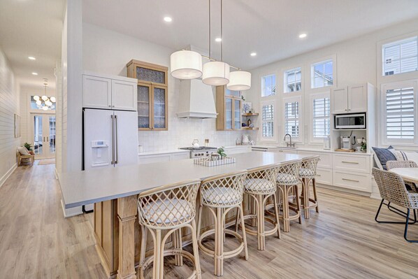 A modern kitchen with a large island, bar stools, and a dining area.
