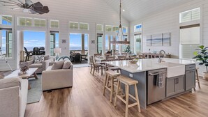 A spacious kitchen with a large island, wooden flooring, and a view of the ocean. - Livin' the Dream 136 TUC (Port Aransas)