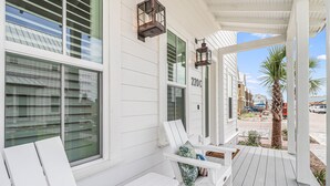 A white porch with two white chairs, a bench, and a palm tree. - Rose All Day 220 Esc-c (Port Aransas)