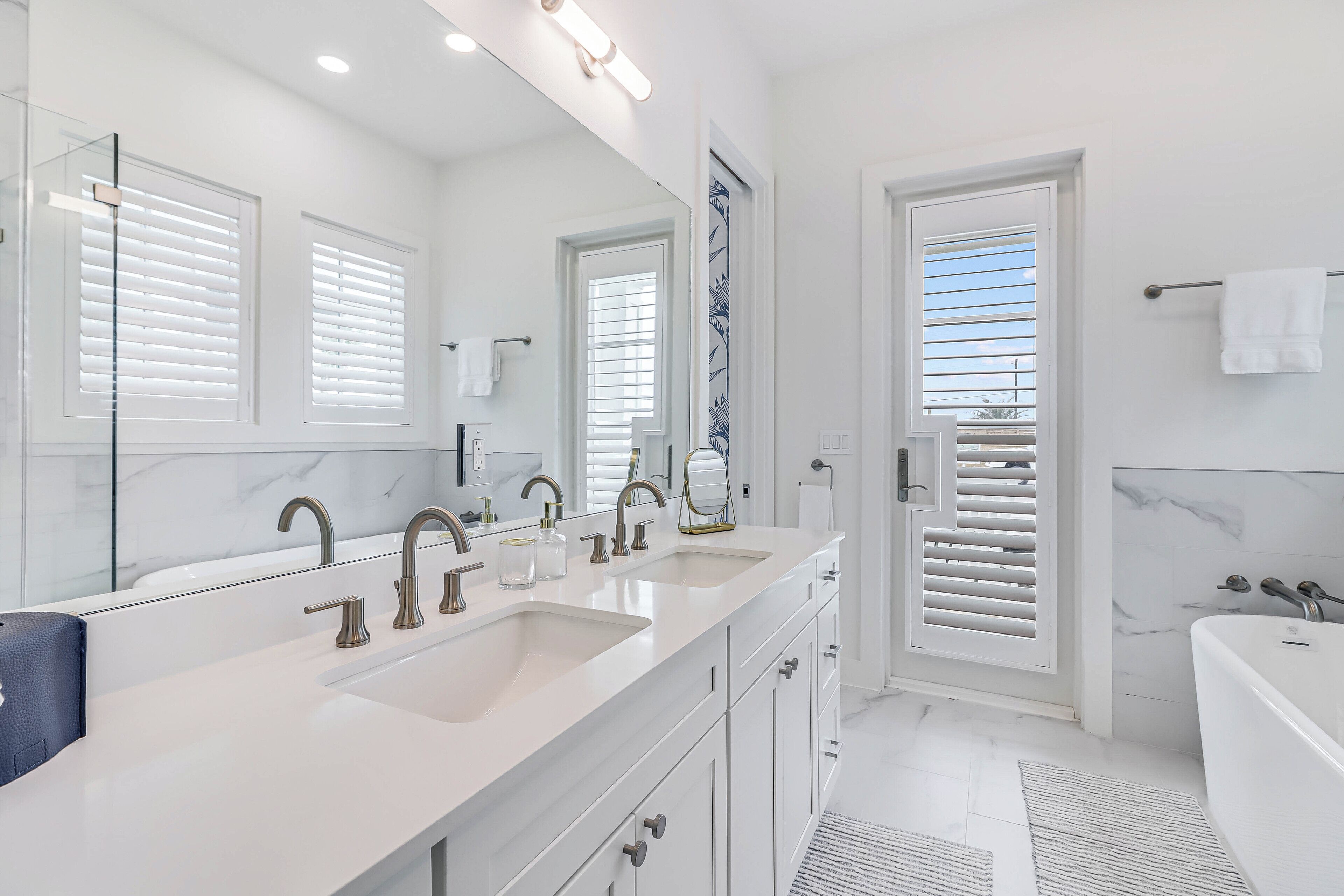 Un baño moderno con lavamanos doble, un espejo grande y una bañera.