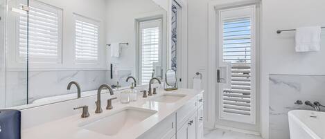 Un baño moderno con lavamanos doble, un espejo grande y una bañera.