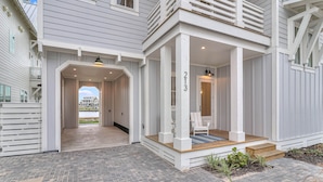 A two-story house with a covered porch, a number '213' on the front, and a pathway leading to the entrance. - Casa Del Sol 213 TEA (Port Aransas)