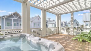 Ein überdachter Außenbereich mit Whirlpool, Holzterrasse und weißen Geländern.