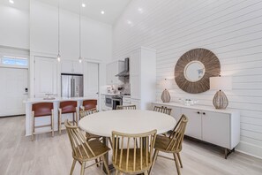 A modern kitchen with white cabinetry, a central island, and pendant lighting.