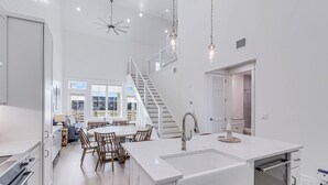 Une cuisine moderne dotée d’un îlot central, d’un coin repas avec des chaises en bois et d’un escalier menant à un niveau supérieur.