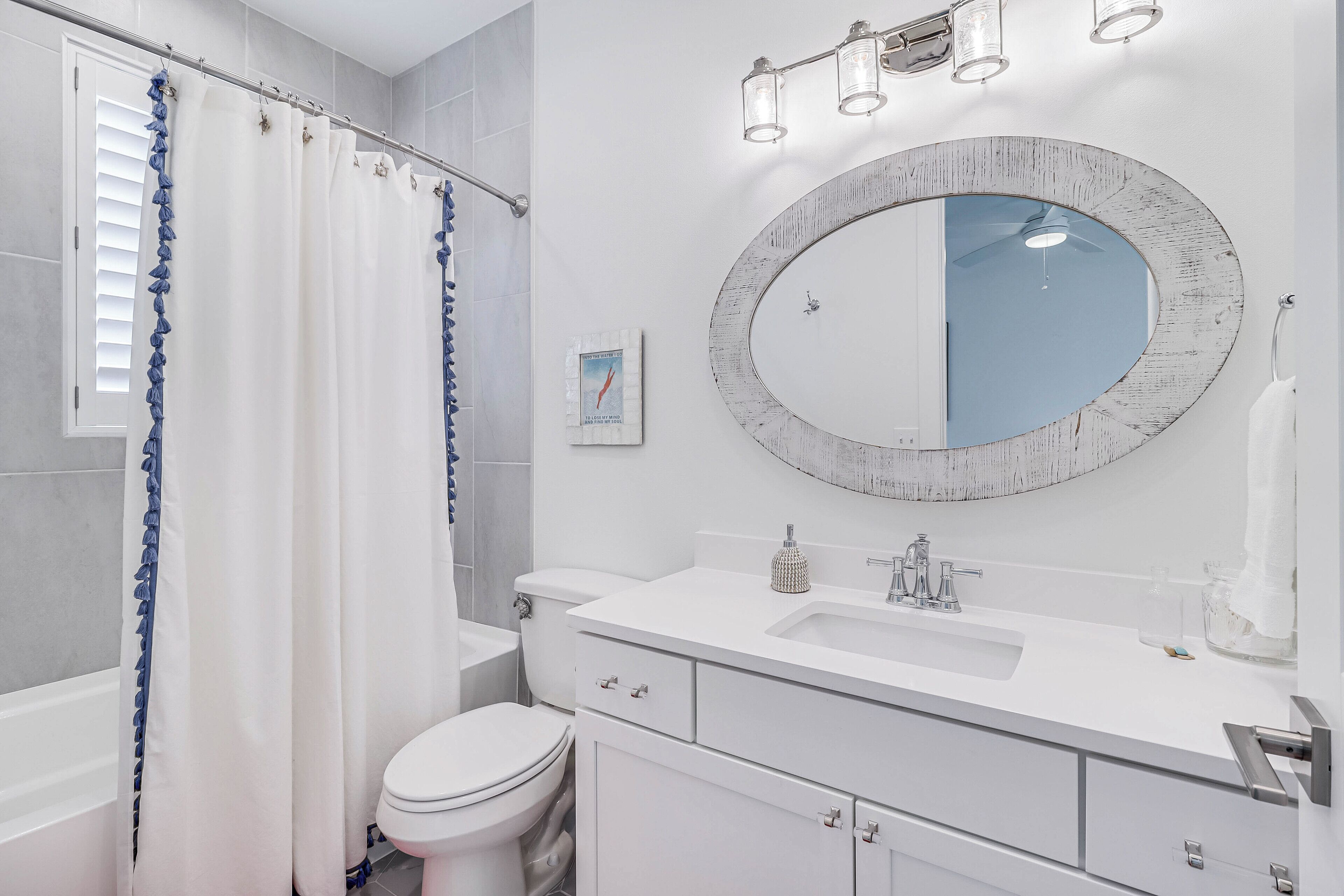 A modern bathroom with a white vanity, a round mirror, and a shower curtain.