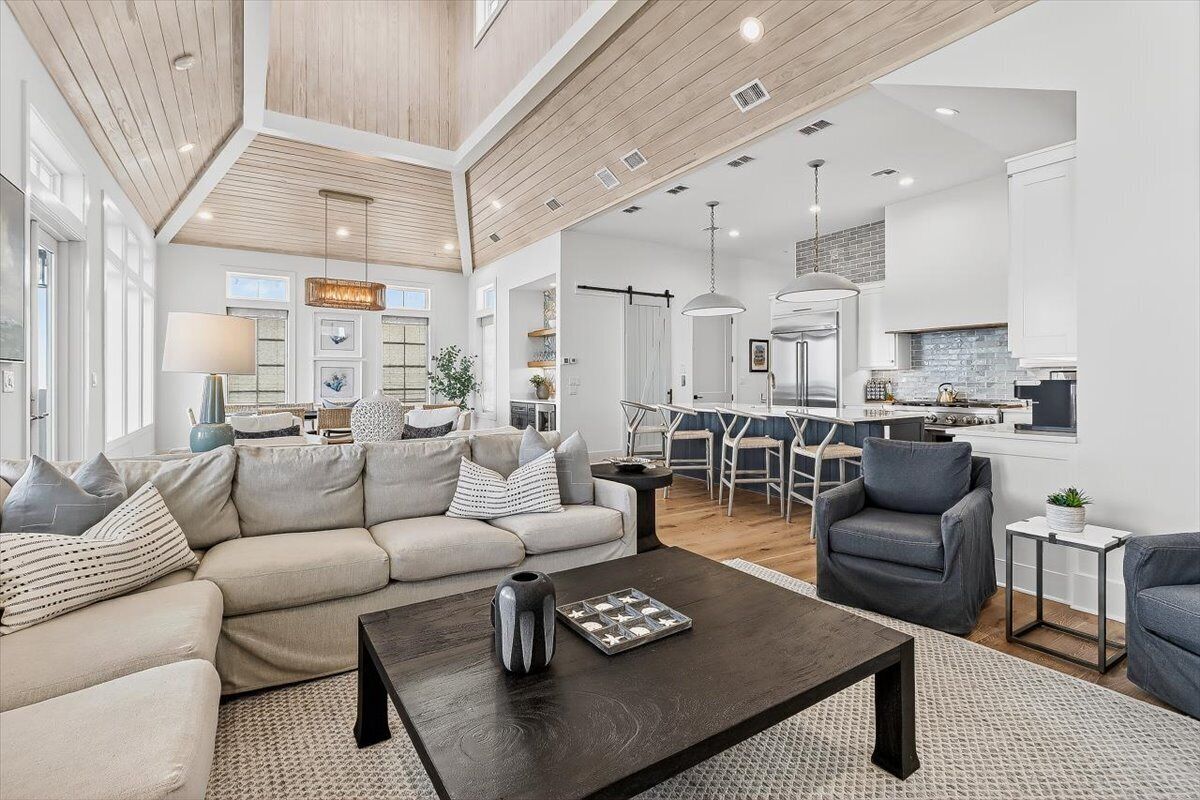 A spacious living area with a sofa, coffee table, and seating, a kitchen with modern appliances, and a dining area with chairs.