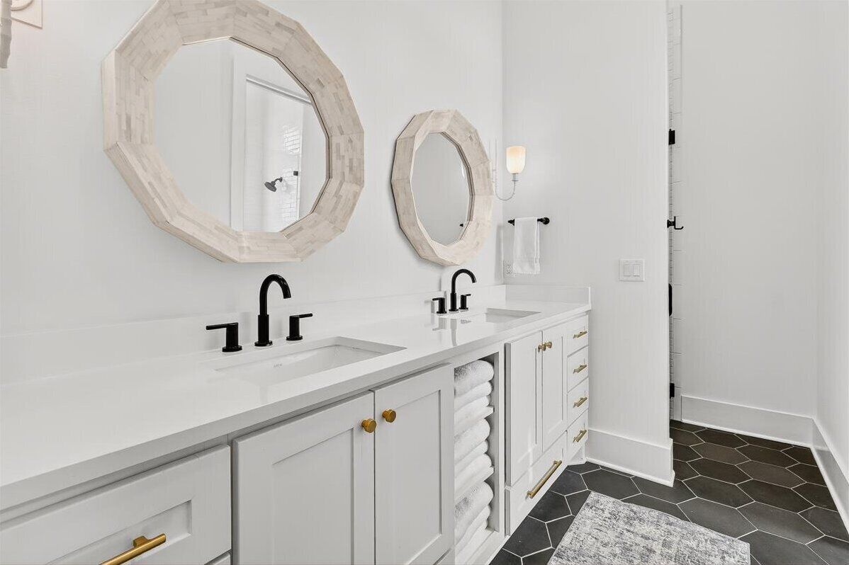 A bathroom with a white vanity, two sinks, and two large mirrors.