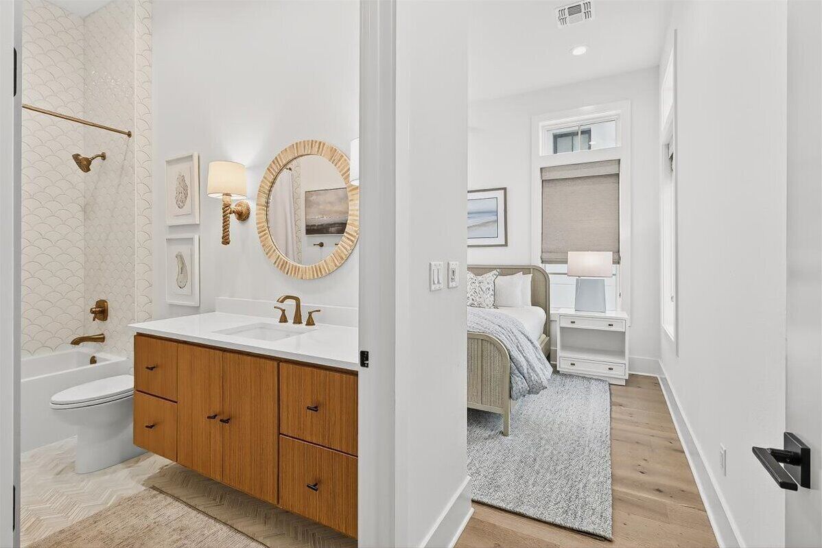 A modern bathroom with a white sink, wooden vanity, and a round mirror.