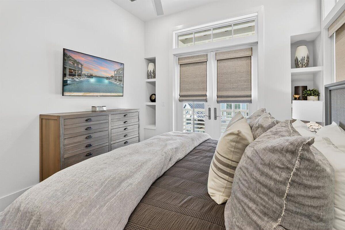 A bedroom with a bed, a dresser, a painting, and a window with blinds.
