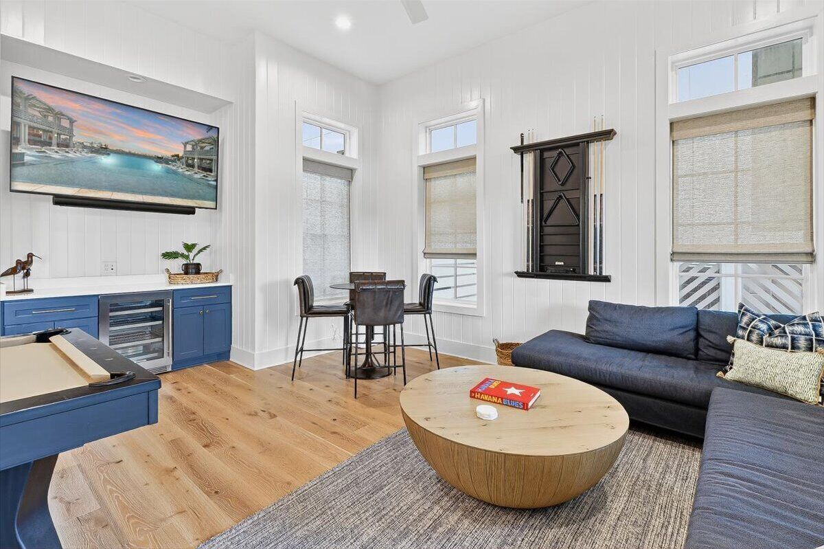 A modern living room with a pool table, a sofa, and a TV mounted on the wall.